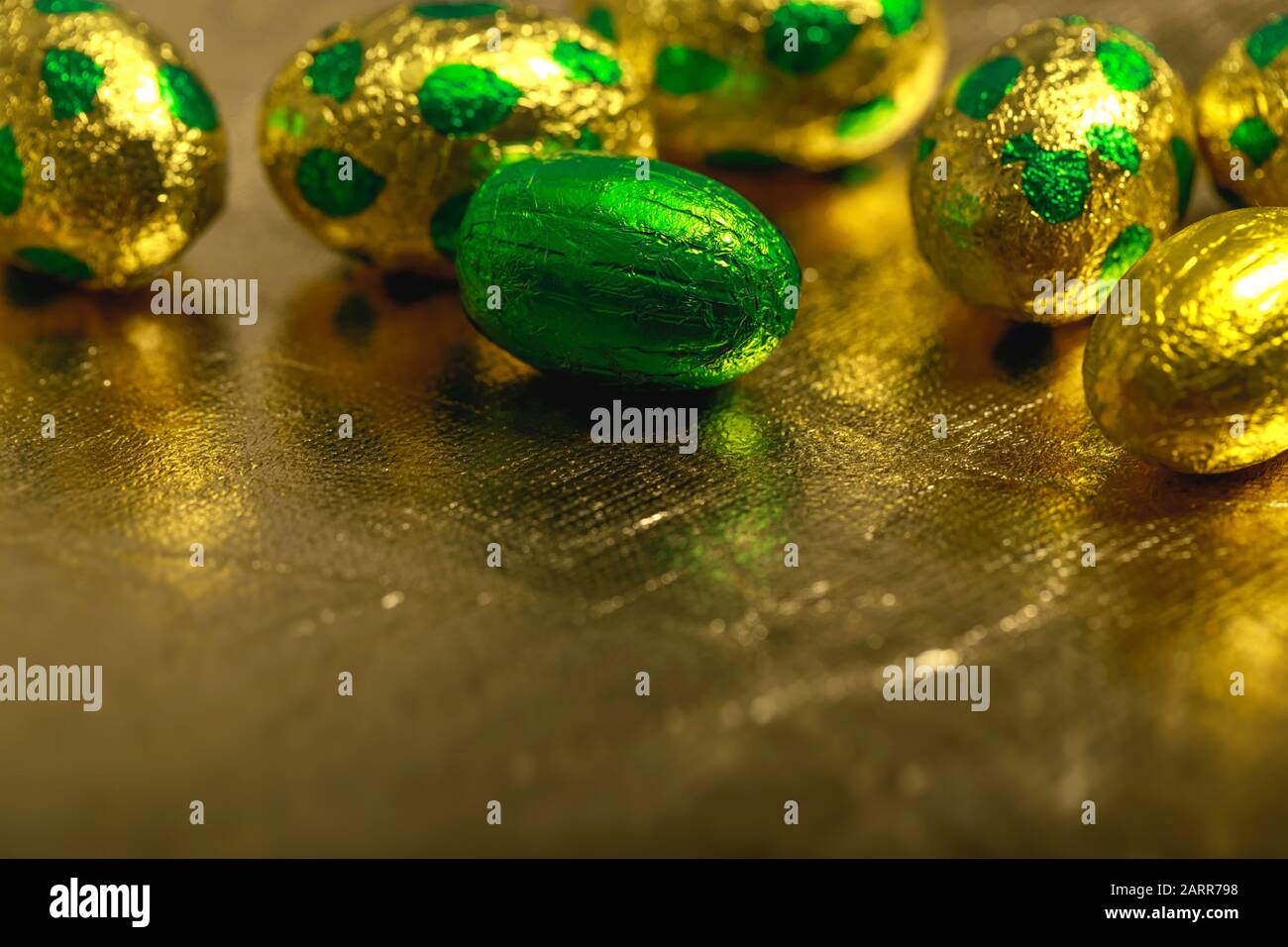 Uova di pasqua al cioccolato avvolte in oro giallo e lamina di colore verde su sfondo dorato. Foto Stock