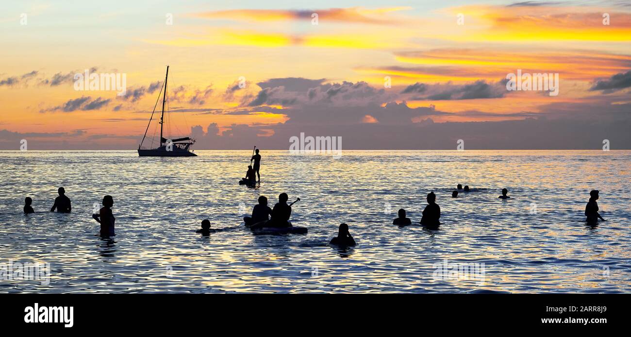 Silhouette di uno yacht e un gruppo di turisti in acque calme lungo la Spiaggia Bianca di Boracay Island a colorato tramonto, Filippine Foto Stock