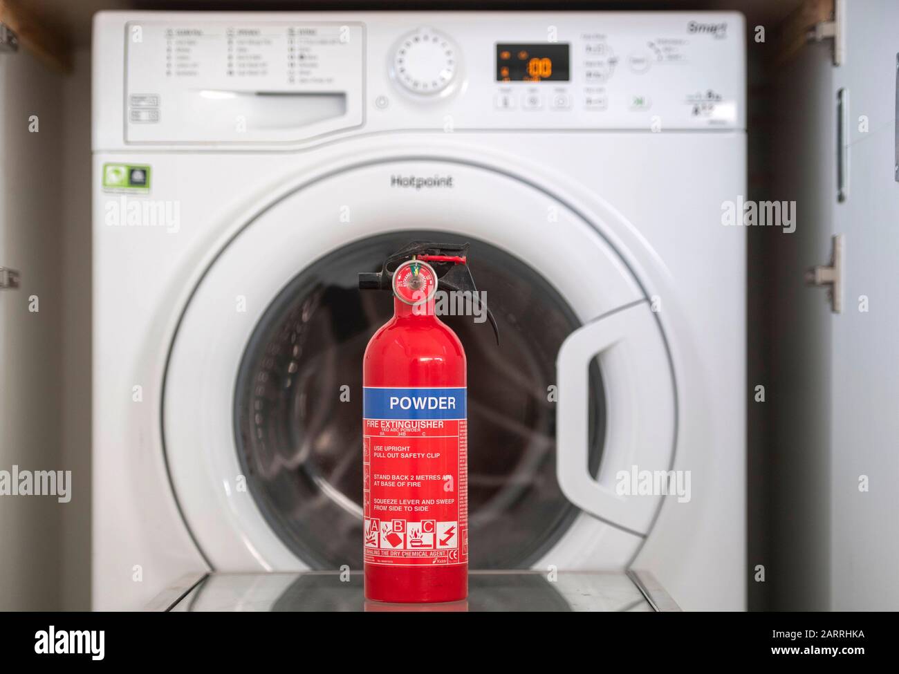 Una lavatrice Hotpoint che è su una lista di richiamo di apparecchi incendiati con un estintore. Si tratta di una delle numerose macchine che possono provocare incendi a causa di un meccanismo di porta surriscaldato. Circa il 20% delle lavatrici Hotpoint e Indesit vendute dal 2014 sono interessate da un guasto di sicurezza e devono essere richiamate. Foto Stock