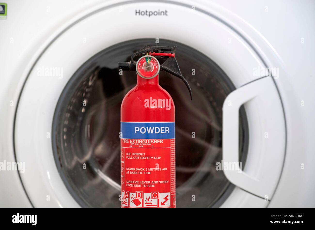 Una lavatrice Hotpoint che è su una lista di richiamo di apparecchi incendiati con un estintore. Si tratta di una delle numerose macchine che possono provocare incendi a causa di un meccanismo di porta surriscaldato. Circa il 20% delle lavatrici Hotpoint e Indesit vendute dal 2014 sono interessate da un guasto di sicurezza e devono essere richiamate. Foto Stock