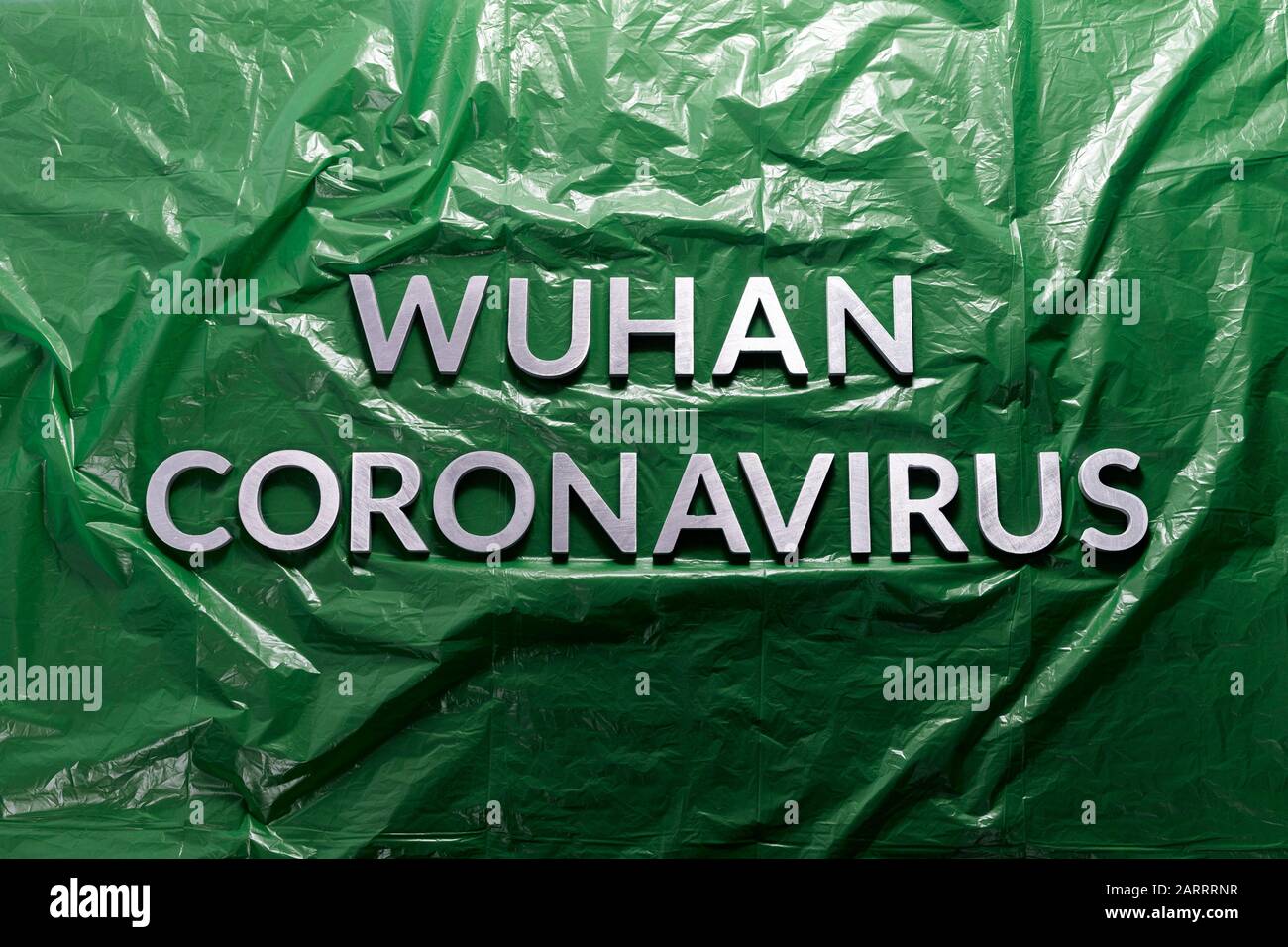 parole wuhan coronavirus posato con lettere metalliche su verde sbriciolato sfondo in pellicola di plastica - disposizione piatta con composizione Foto Stock