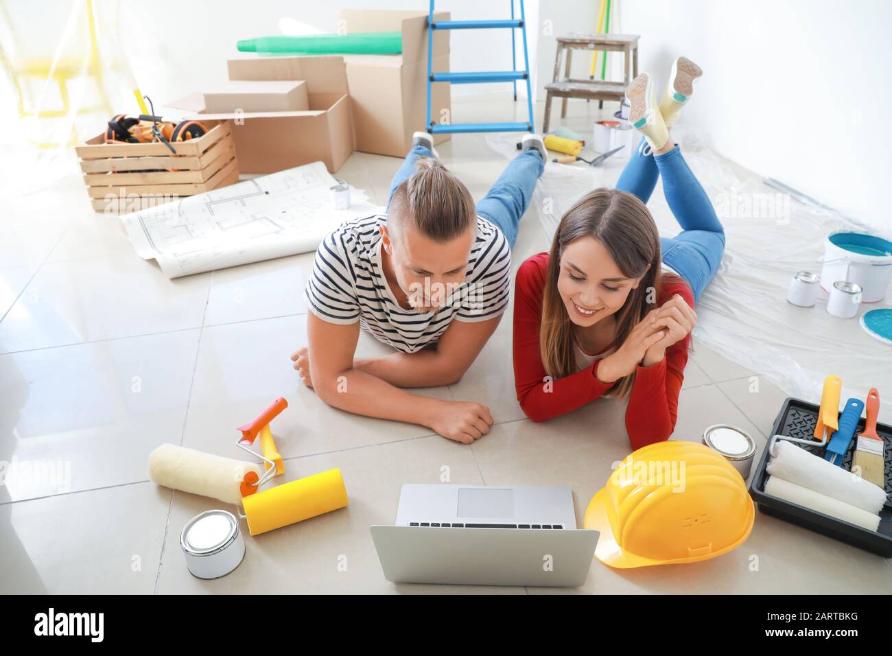 Felice coppia giovane con laptop riparazione di pianificazione nella loro nuova casa Foto Stock