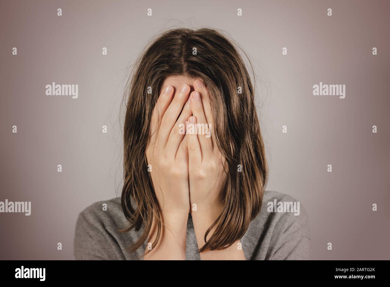 Donna copre il viso nelle mani. Concetto di disperazione, depressione, perdita o condizione mentale Foto Stock