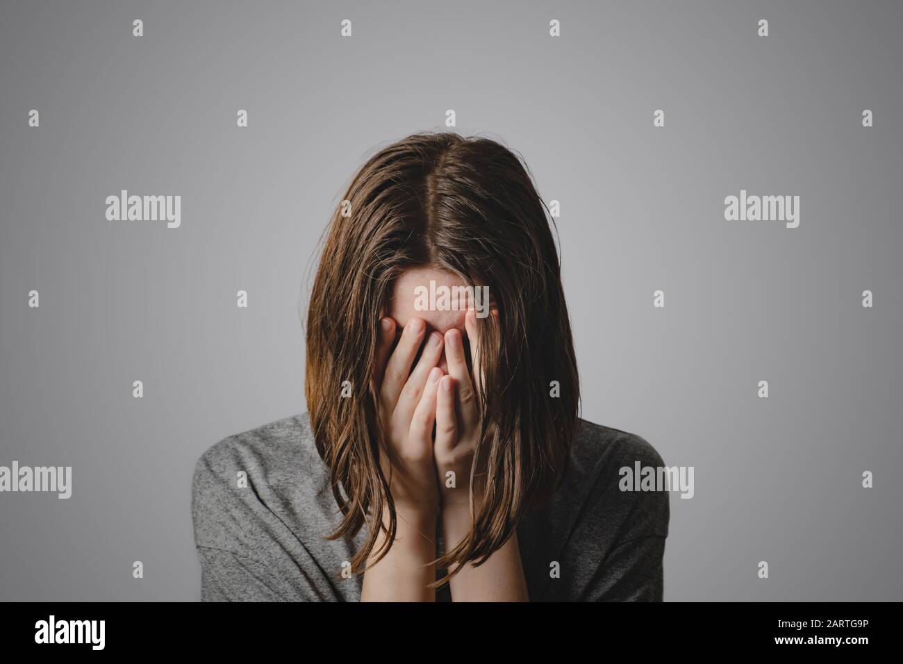 Donna copre il viso nelle mani. Concetto di disperazione, depressione, perdita o condizione mentale Foto Stock