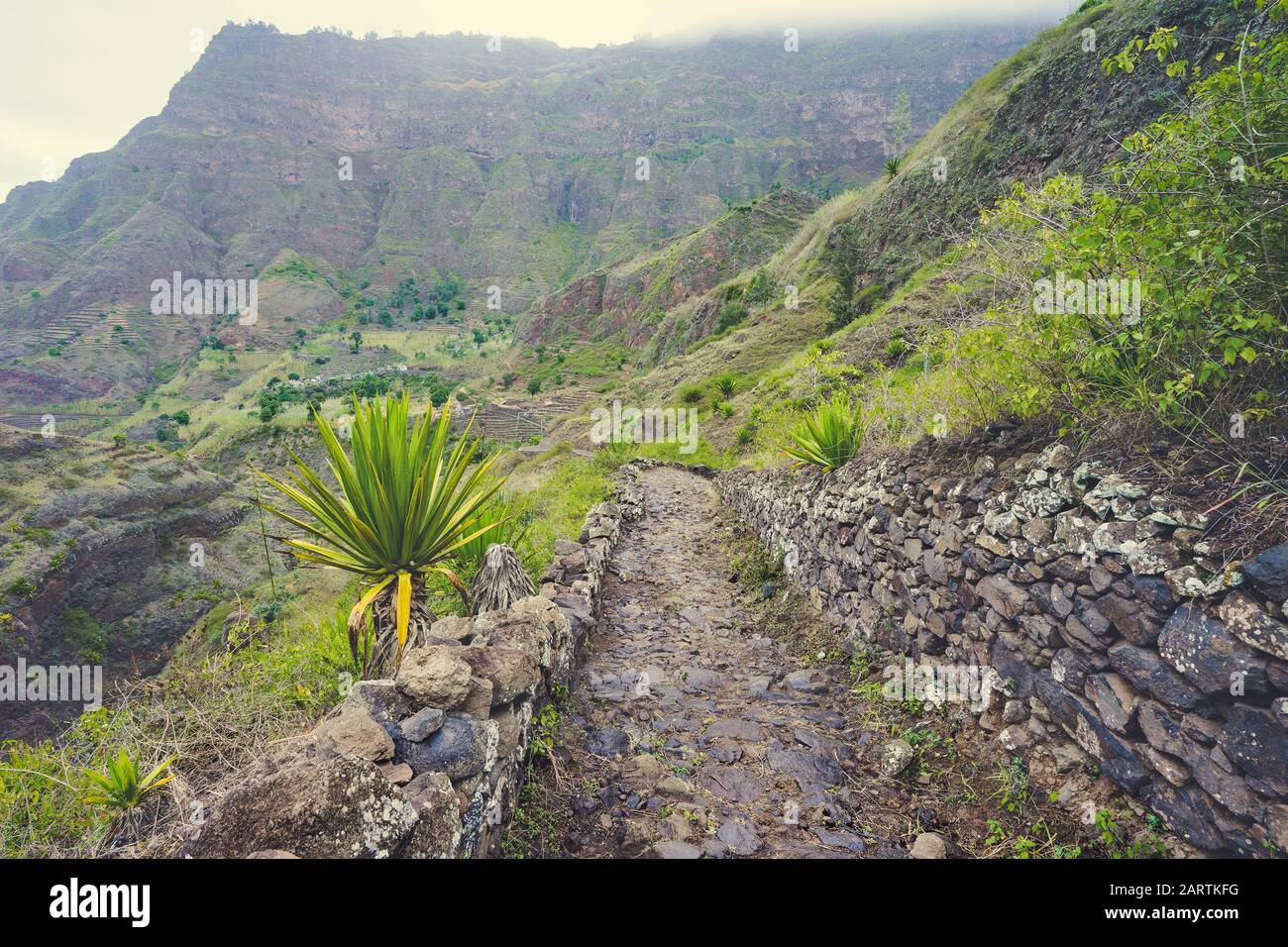 Santo Antao Capo Verde. Sentiero lastricato che scende lungo la valle. Terreno roccioso di alte catene montuose e profonde gole sullo sfondo. Foto Stock