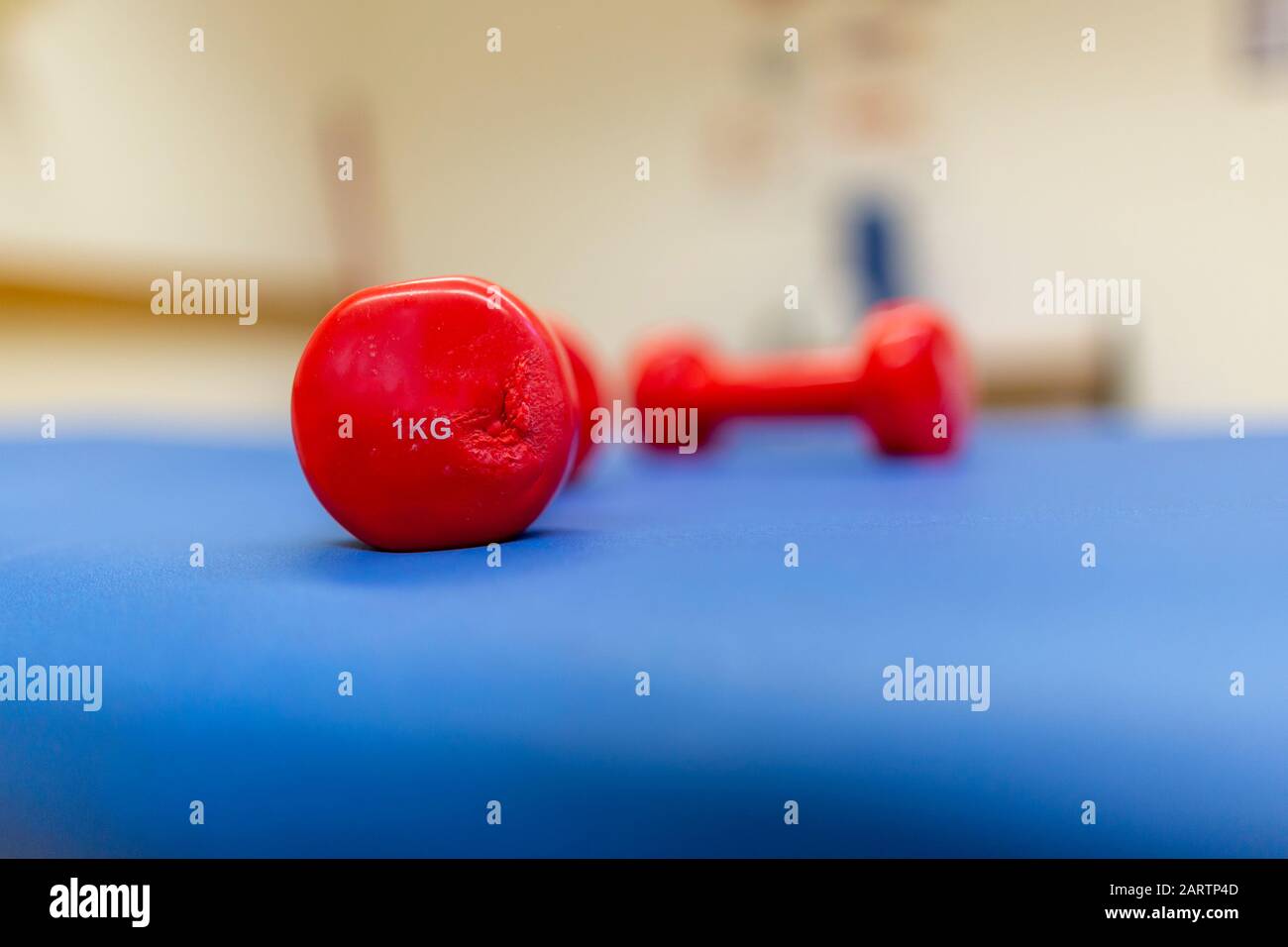 Il peso di un chilo rosso si trova su un tappetino blu Foto Stock