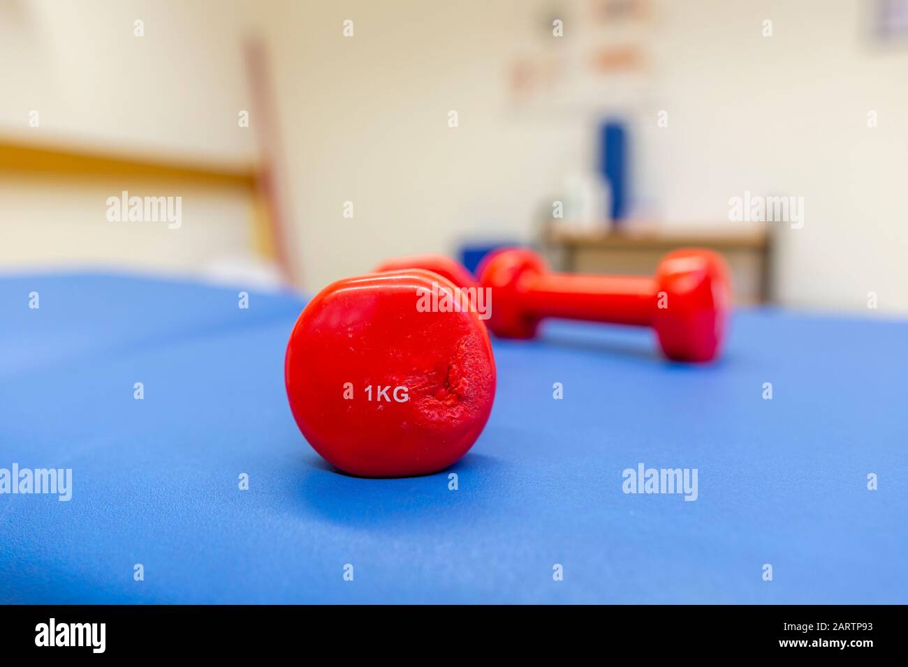 Il peso di un chilo rosso si trova su un tappetino blu Foto Stock