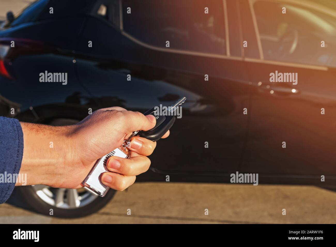 La mano dell'uomo preme il tasto sulla chiave dell'auto del telecomando Foto Stock