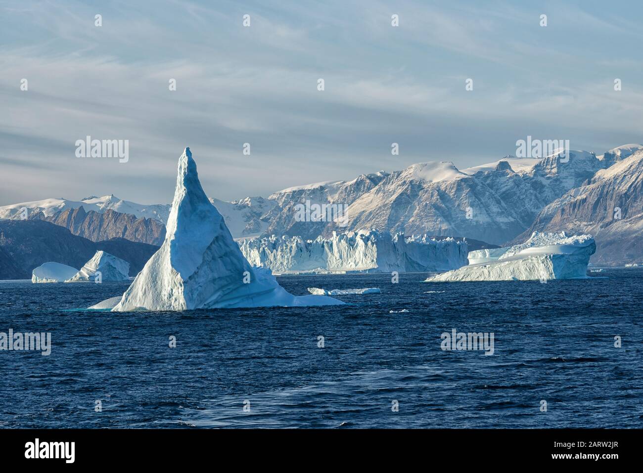 Alba in fiordo Scoresby Sund. Ghiaccioli galleggianti di fronte alle montagne innevate. Kangertitivaq, Groenlandia, Danimarca Foto Stock