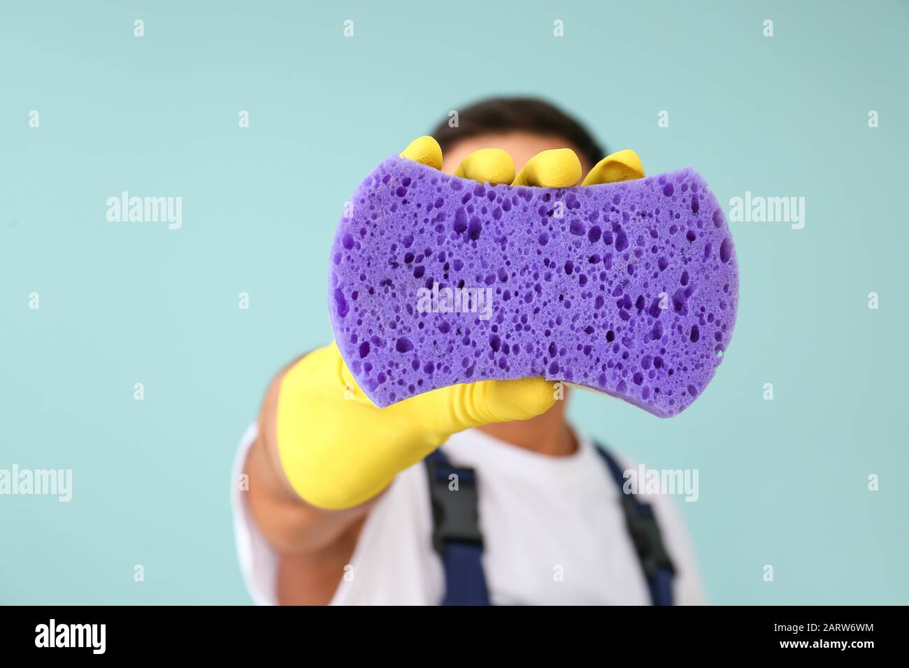 Giovane uomo con spugna e mop su sfondo colorato Foto Stock