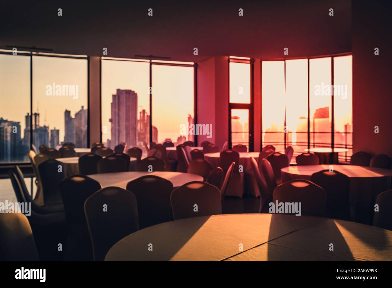 immagine sfocata astratta della sala da pranzo vuota con skyline della città e sfondo del cielo del tramonto - Foto Stock