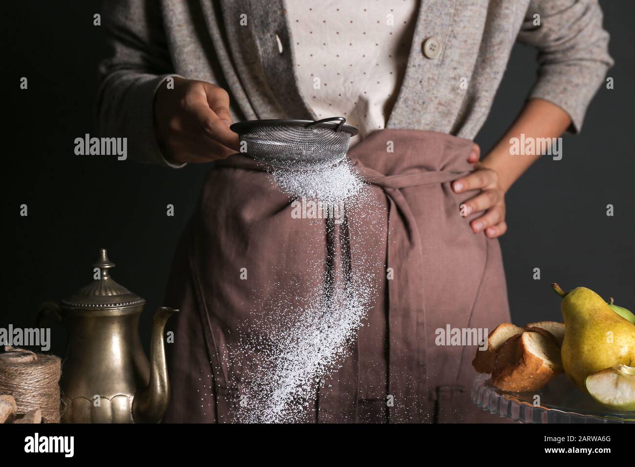 Donna spolverare la polvere di zucchero attraverso il setaccio, closeup Foto Stock