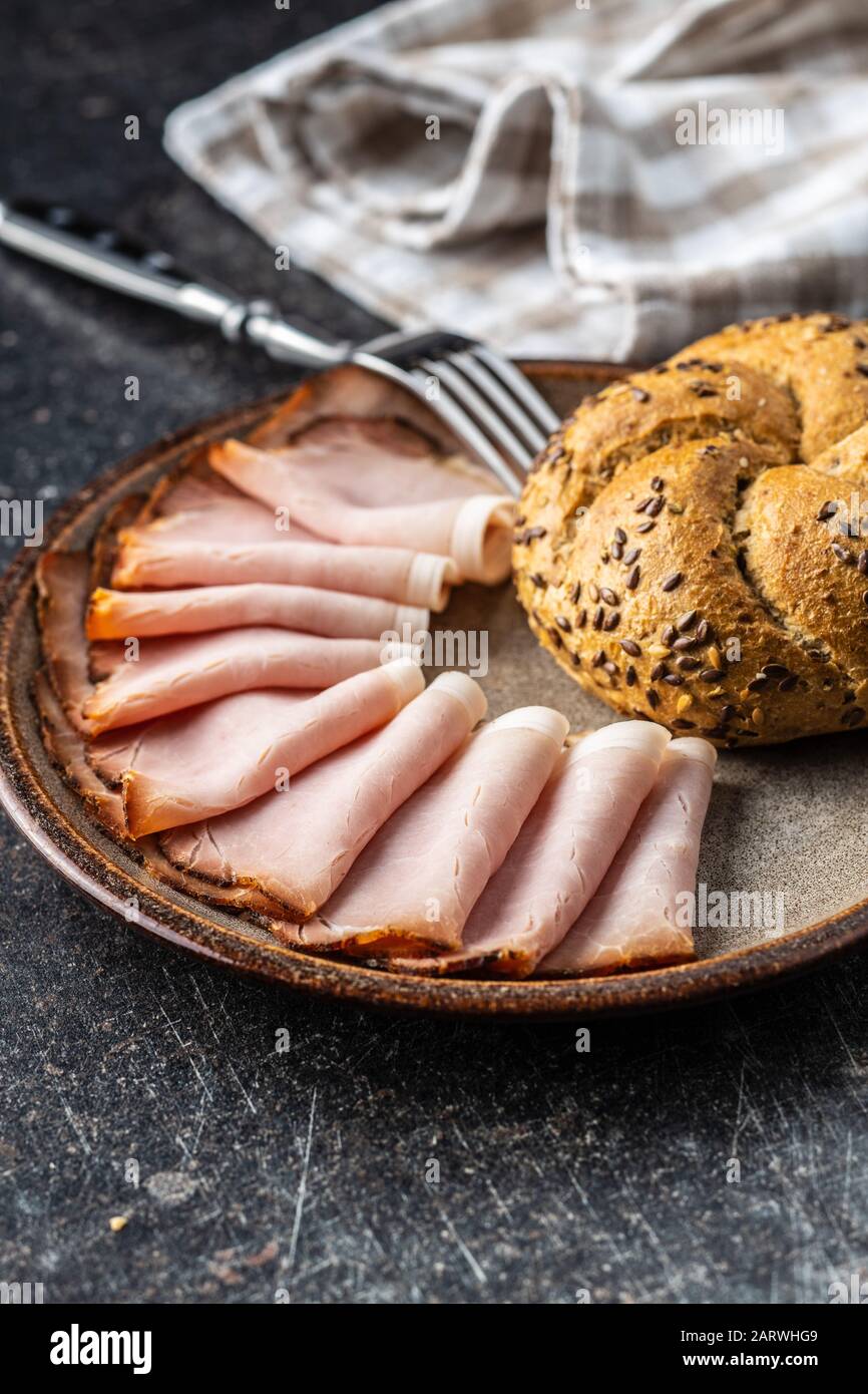 Prosciutto affumicato a fette. Carne di maiale saporita e panino su piatto. Foto Stock