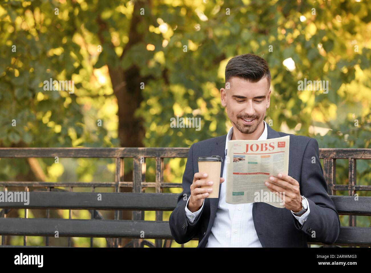 Ritratto di bell'uomo d'affari con una tazza di caffè leggendo il giornale all'aperto Foto Stock