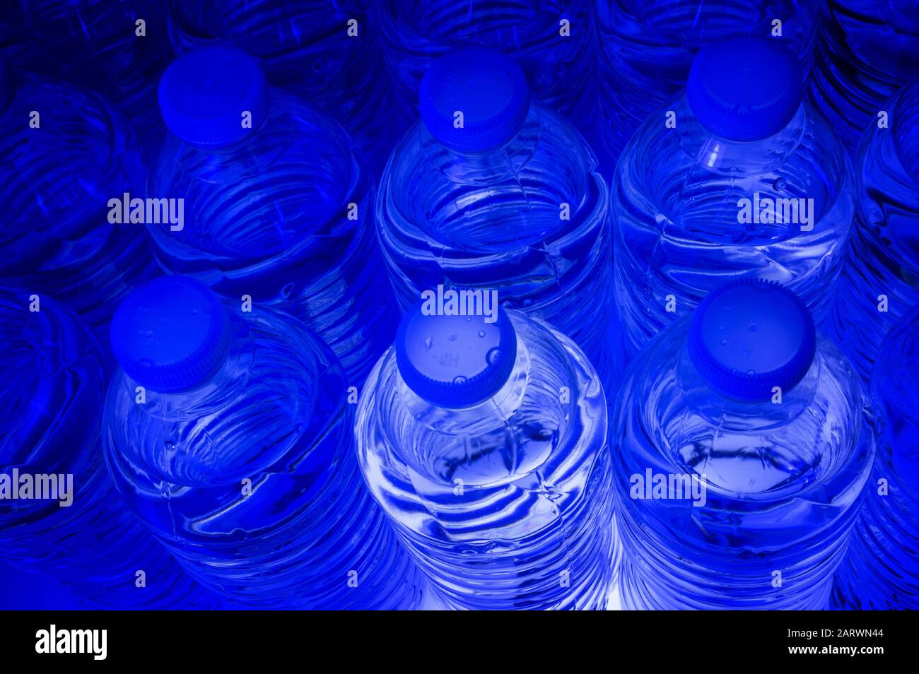 Studio ancora vita immagine di un gruppo di bottiglie di acqua illuminato dal fondo con luce blu Foto Stock