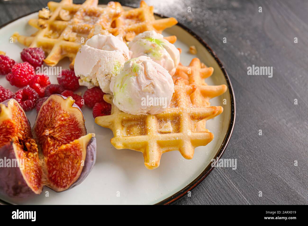 Piatto con gustosi waffle, frutti di bosco e fichi sul tavolo, primo piano Foto Stock