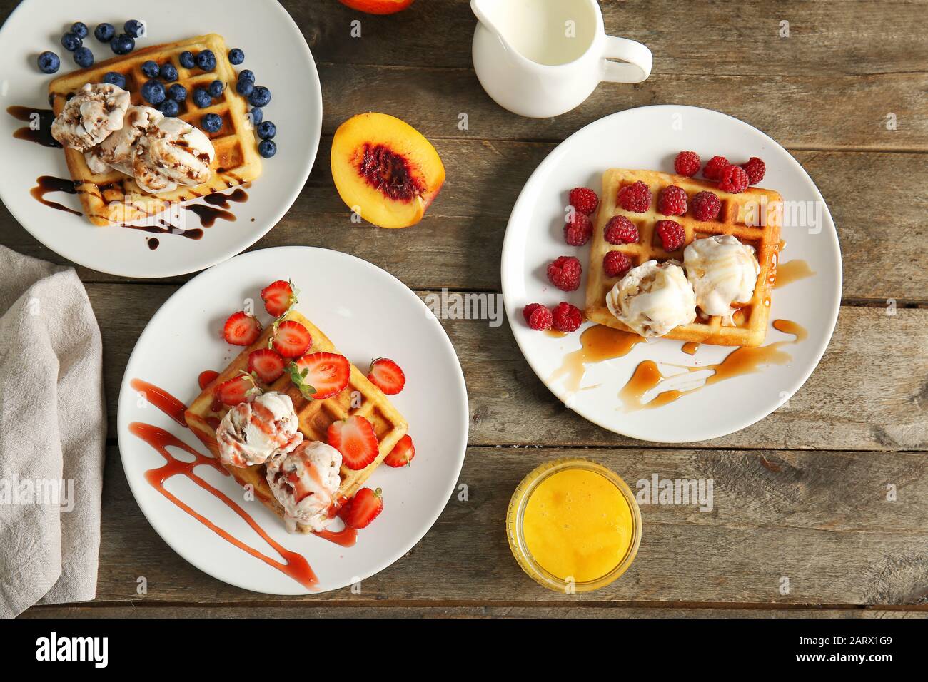 Piatti con gustosi waffle, frutti di bosco e gelato a tavola Foto Stock