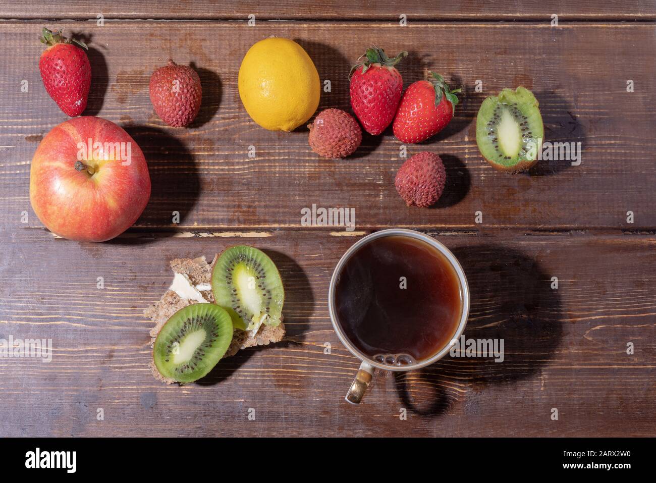 Frutta, tazza di tè e sandwich su tavole di legno Foto Stock