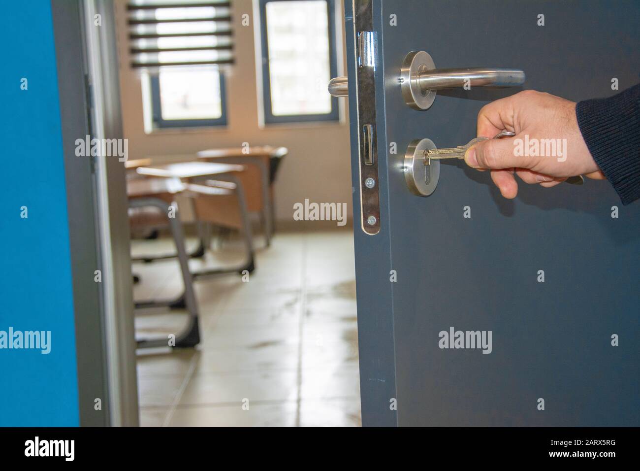 Primo piano della mano inserendo una chiave nella serratura della porta Foto Stock