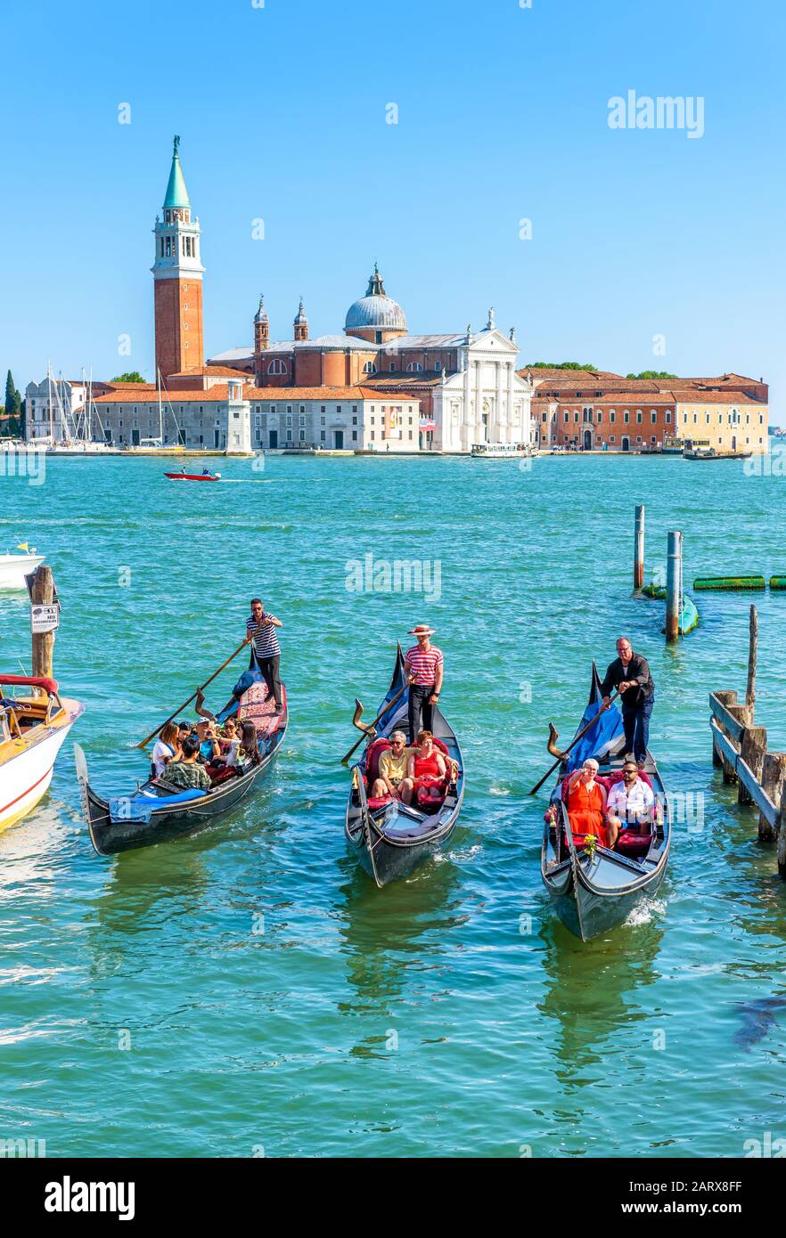 Venezia - 18 maggio 2017: Le gondole navigano contro l'isola di San Giorgio a Venezia. La gondola è il mezzo di trasporto turistico più attraente di Venezia. Conc Foto Stock