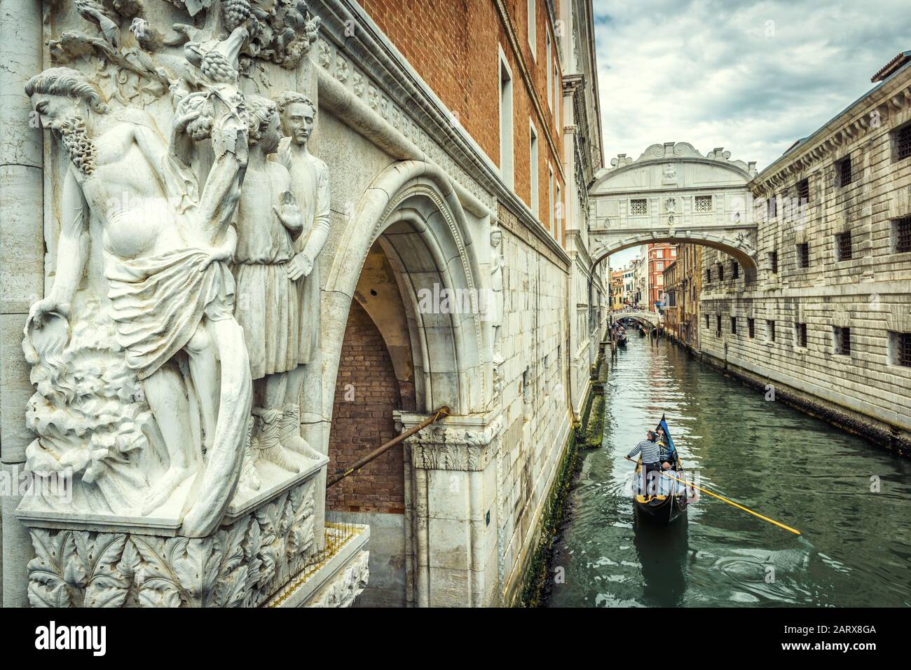 Venezia paesaggio urbano con scultura antica, Italia. Le gondole turistiche navigano sotto il famoso Ponte dei Sospiri. E' un punto di riferimento di Venezia. Romantico viaggio in acqua Foto Stock