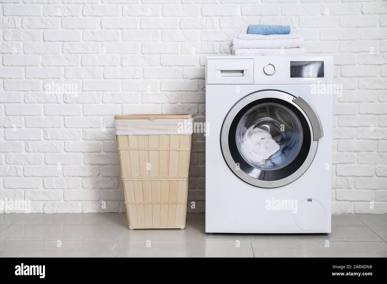 Moderna lavatrice con lavanderia vicino a muro di mattoni bianchi Foto  stock - Alamy