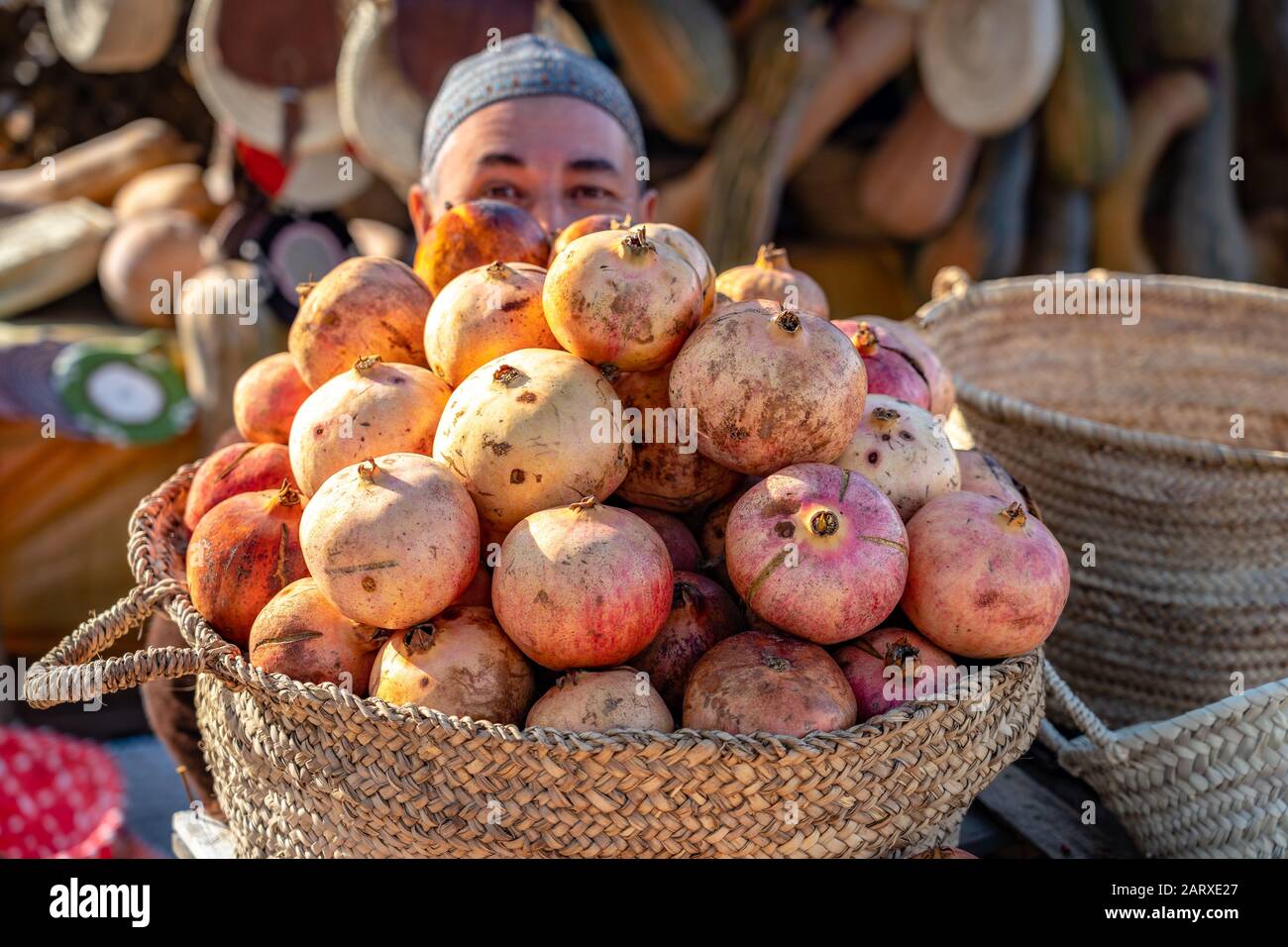 Meknes, Marocco - Amichevole venditore nascosto dietro i melograni Foto Stock
