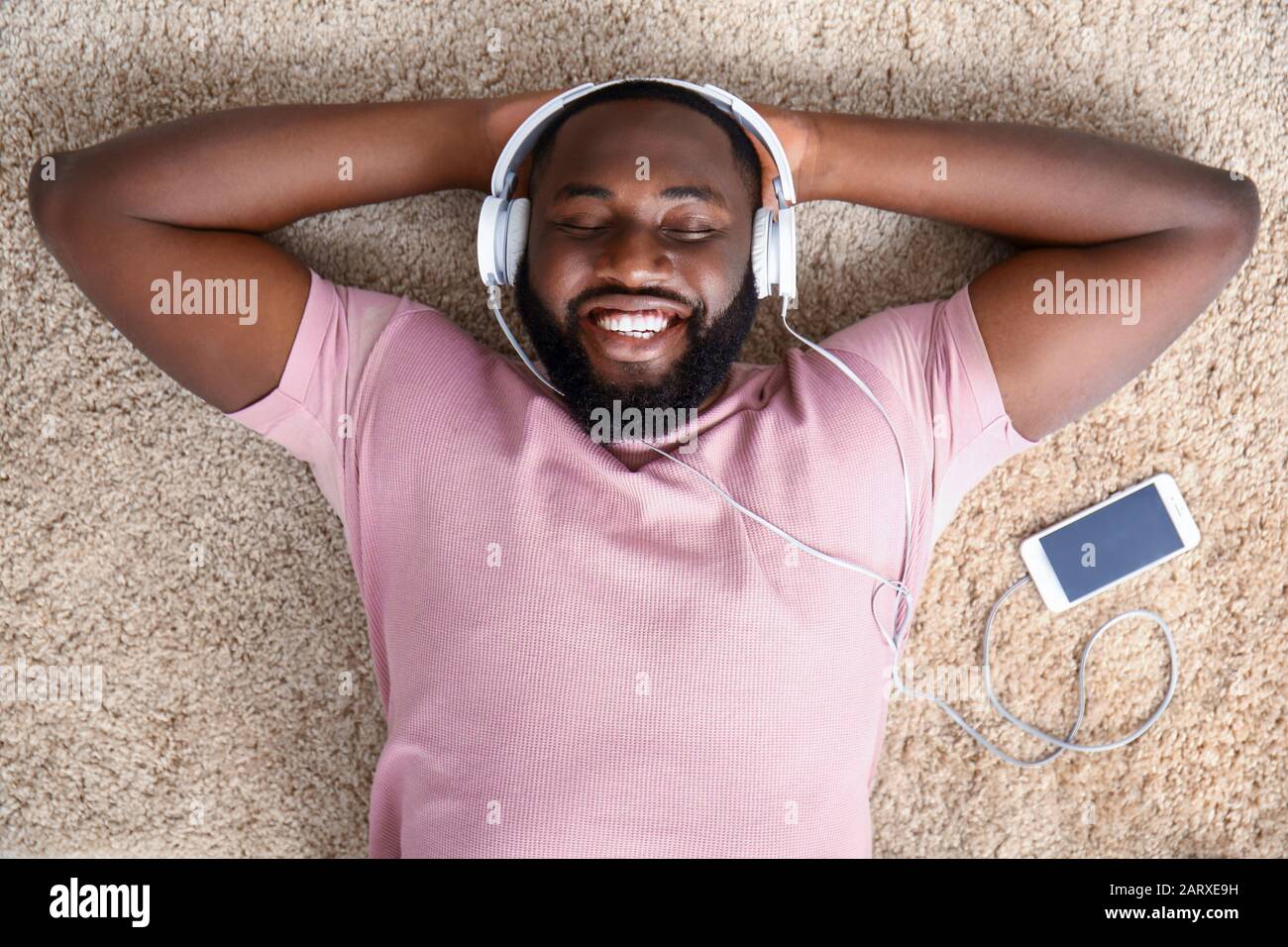 Uomo afro-americano che ascolta la musica a casa, vista dall'alto Foto Stock