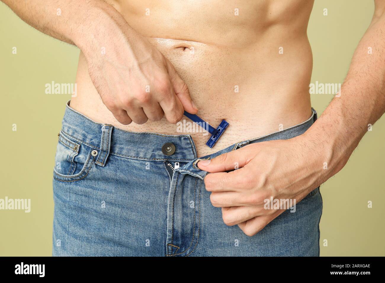 Bel giovane uomo radere il suo corpo su sfondo colorato, closeup Foto Stock