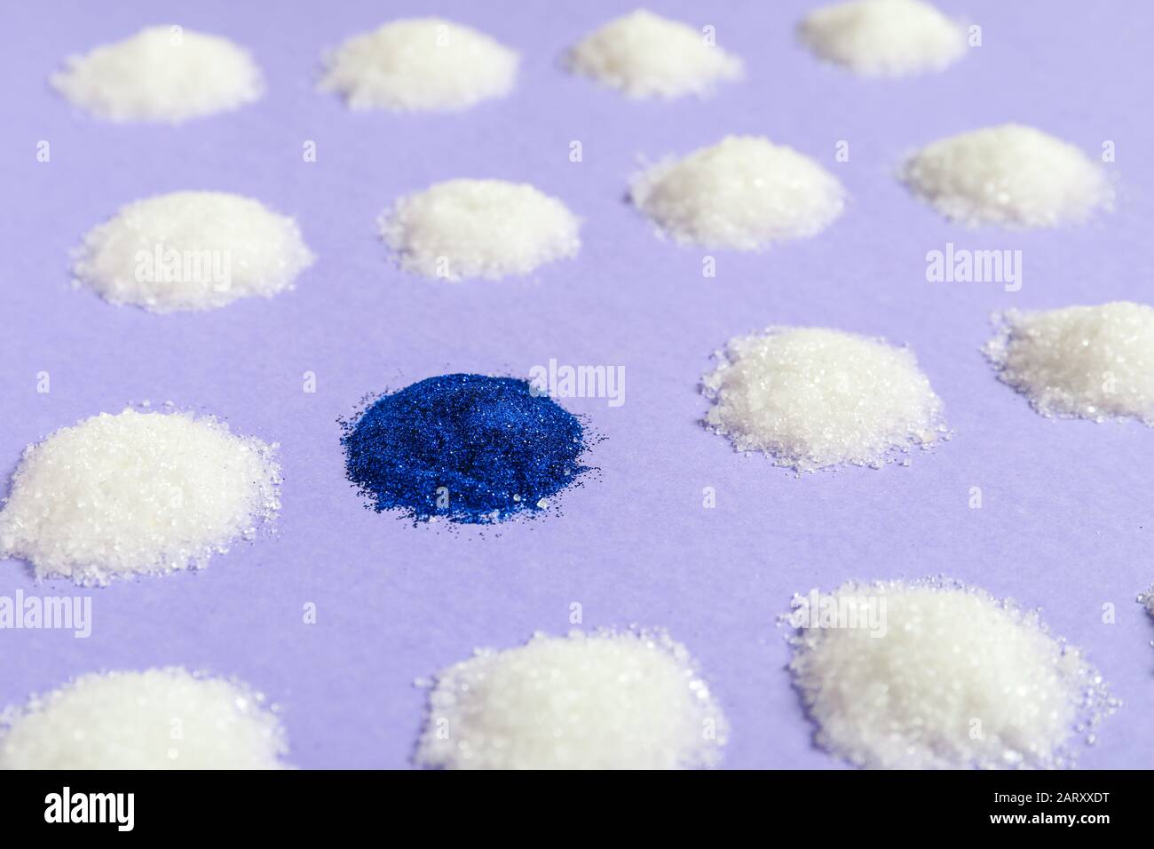 Zucchero blu tra quelli bianchi su sfondo colorato. Concetto di unicità Foto Stock