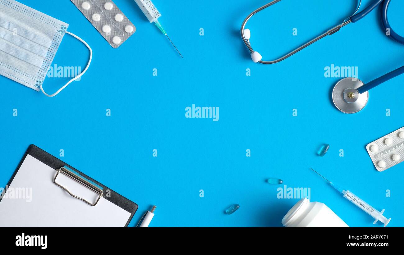 Telaio di apparecchiature mediche, utensili, forniture su sfondo blu. Tavolo medico con appunti medici, stetoscopio, siringhe, pillole. Medico ba Foto Stock