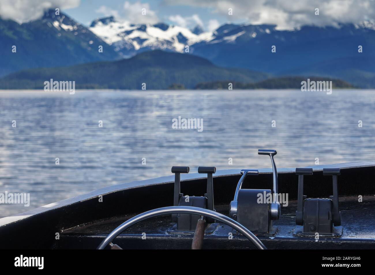 Una piccola barca si sta avvicinando a un ghiacciaio. Ruota dell'imbarcazione a fuoco. Escursione con avvistamento di balene a Juneau, Alaska. Cime di neve sullo sfondo. Foto Stock