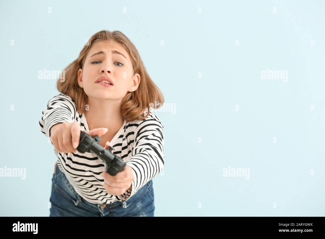 Ragazza adolescente emotivo con game pad su sfondo chiaro Foto Stock