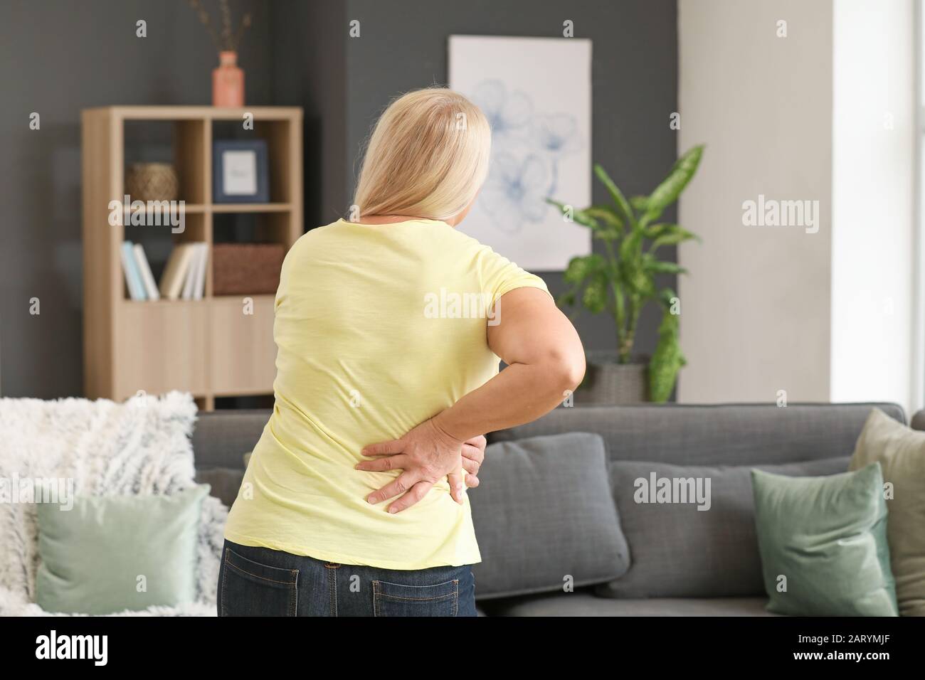 Donna matura che soffre di mal di schiena a casa Foto Stock