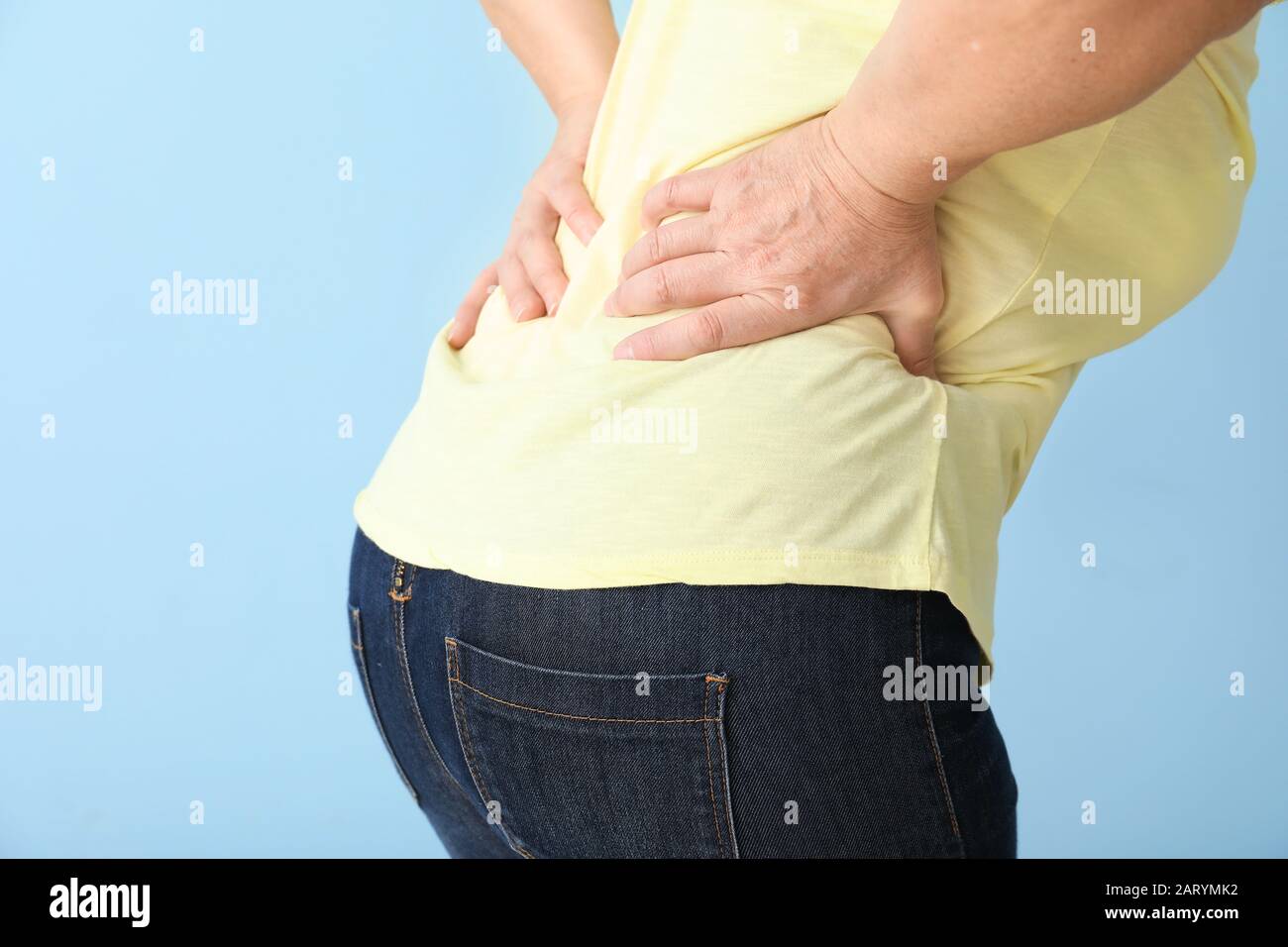 Donna matura che soffre di mal di schiena su sfondo a colori Foto Stock