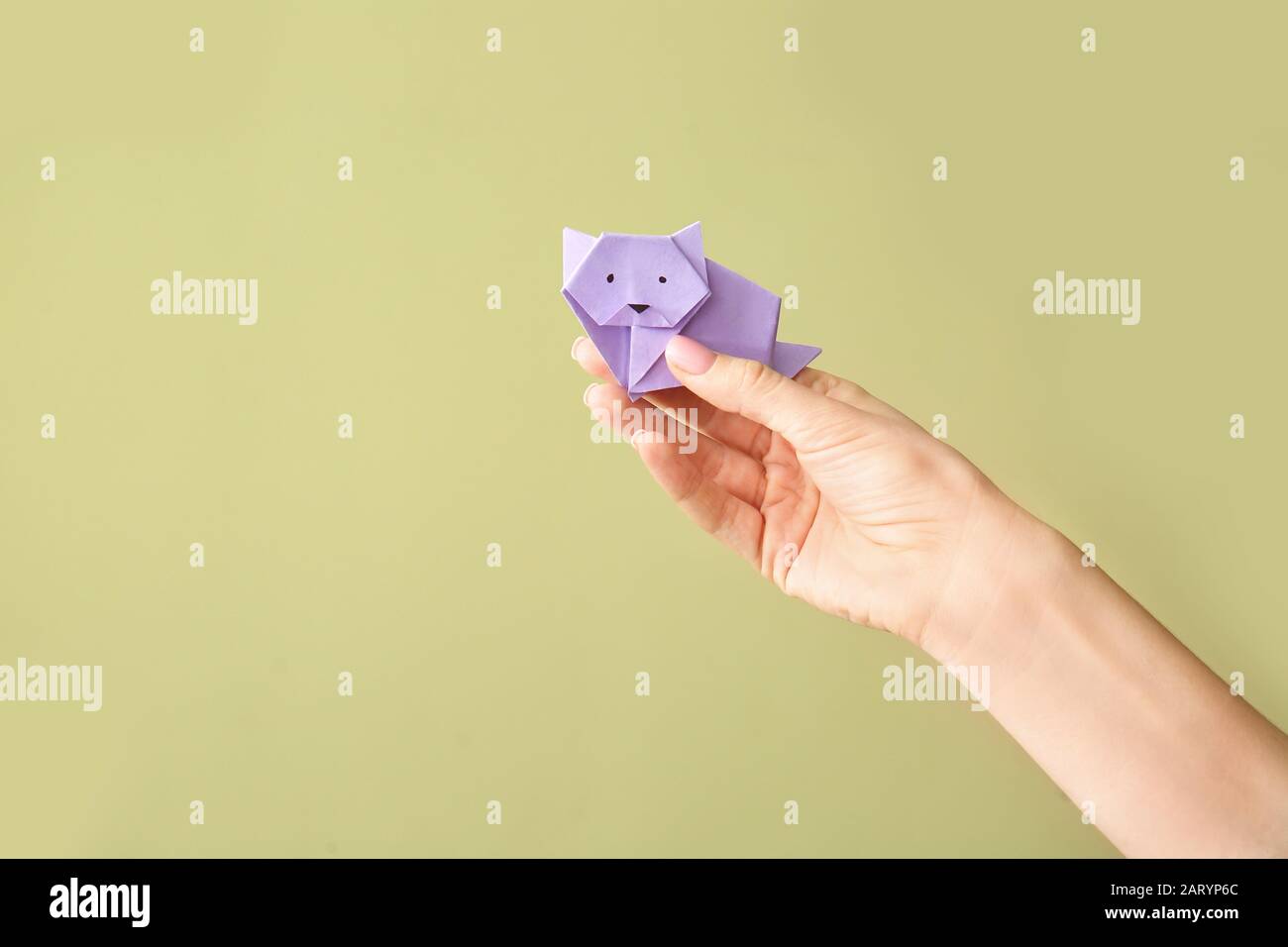 Mano femminile con origami gatto su sfondo a colori Foto Stock