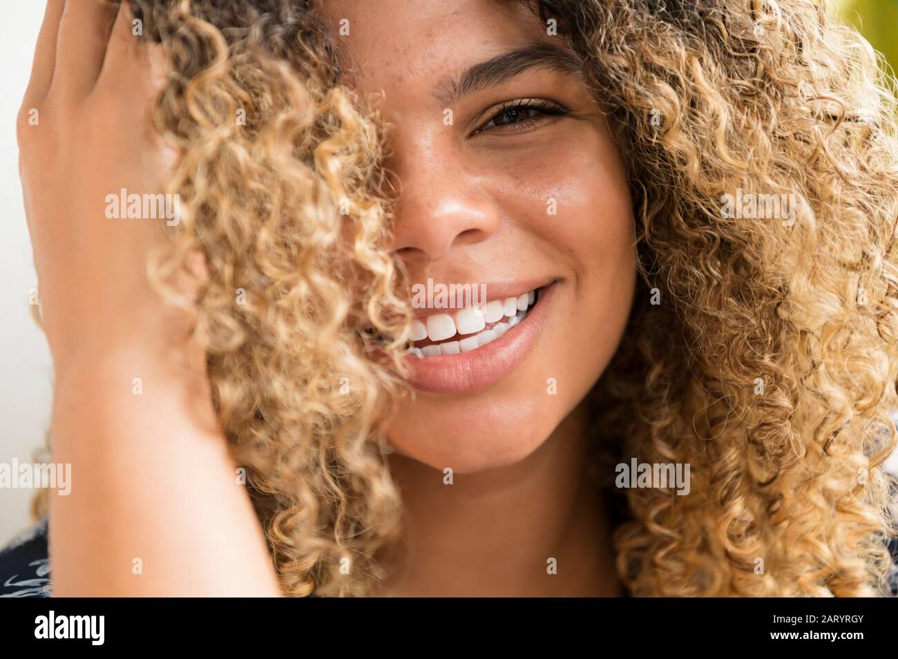 Donna sorridente di toccare i capelli Foto Stock