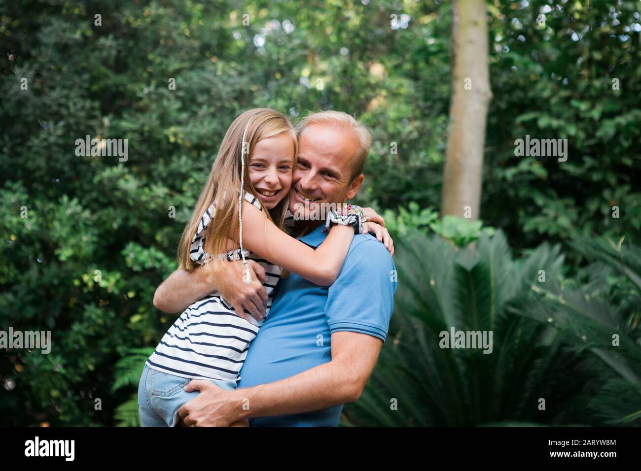 Padre e figlia sorridenti e abbracciati da Bush Foto Stock