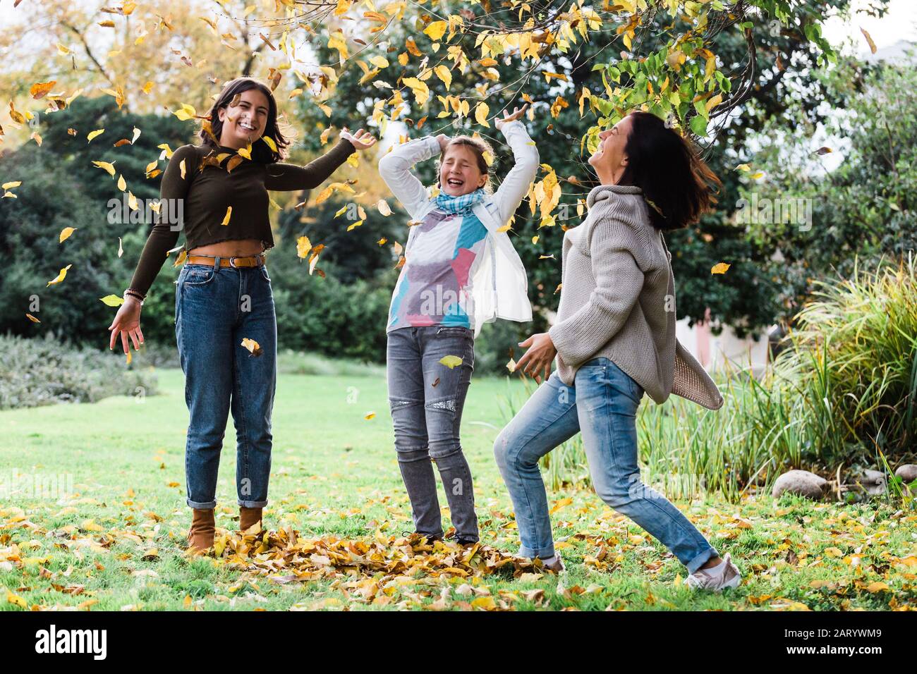 Madre e figlie che giocano in foglie autunnali Foto Stock