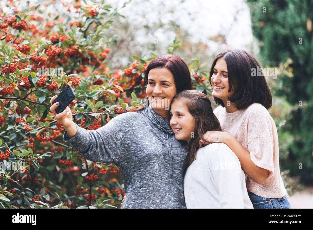 Madre e figlie sorridono e prendono selfie Foto Stock