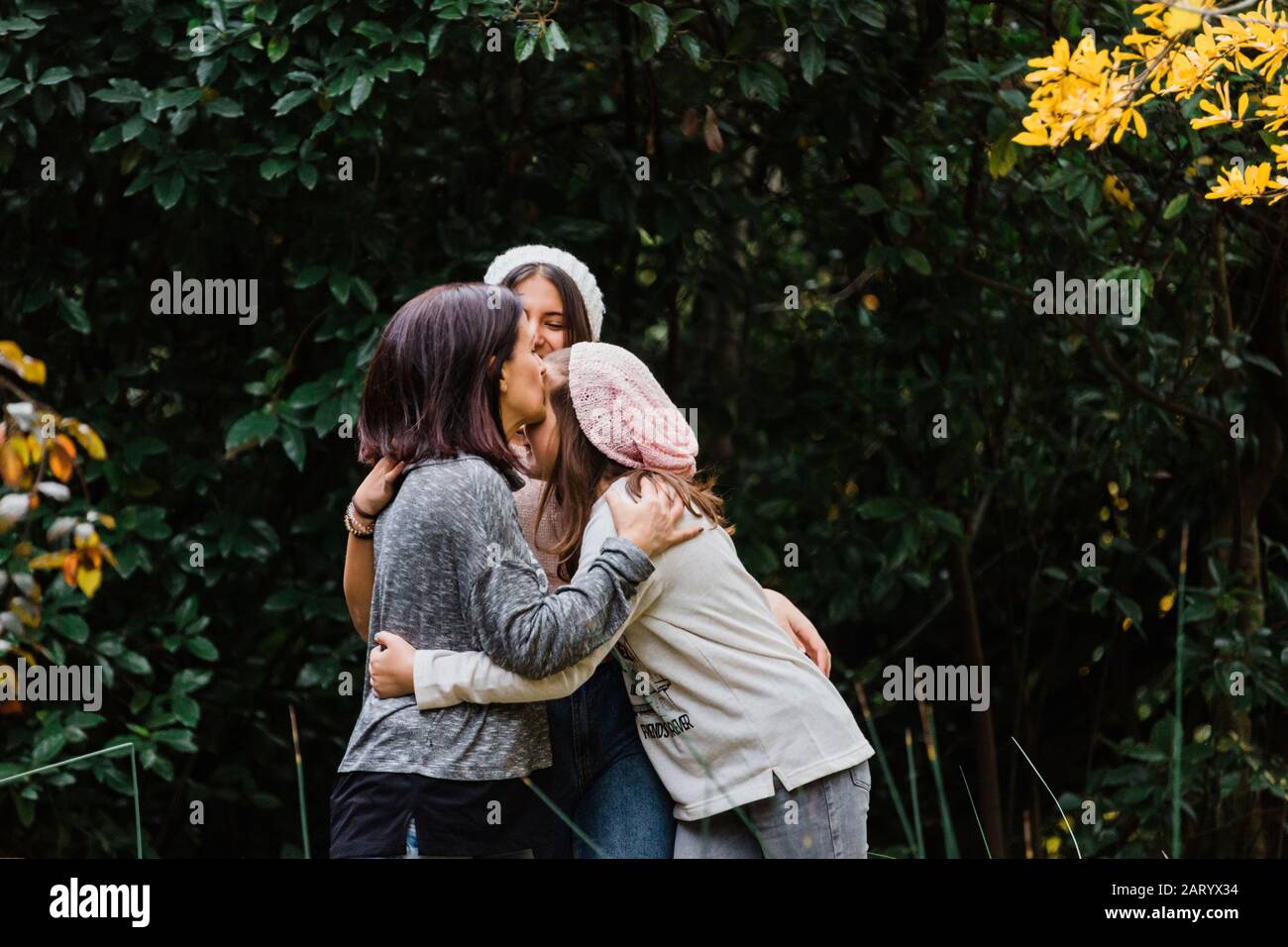 Madre e figlie abbracciate da alberi Foto Stock