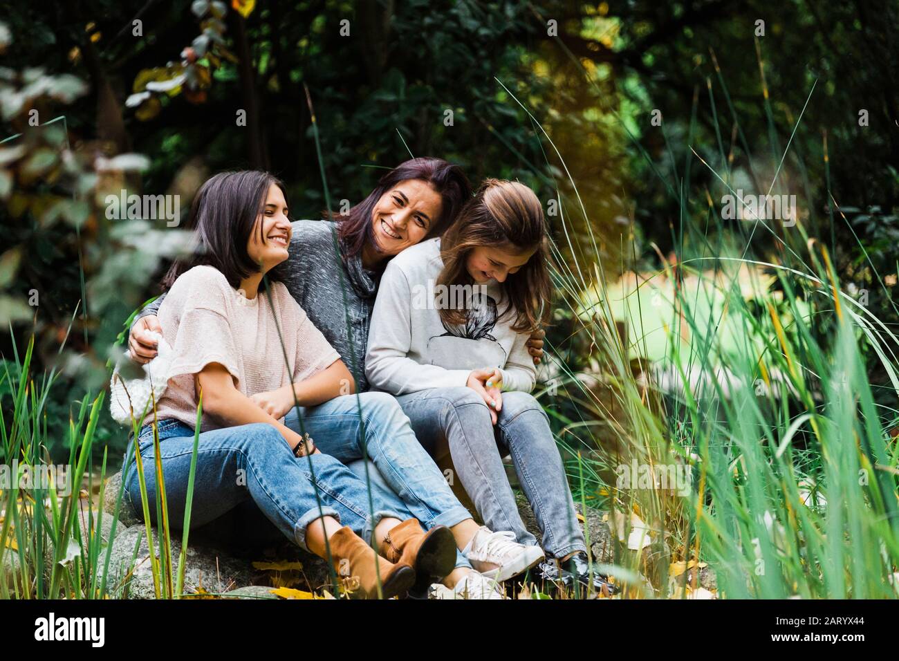 Madre e figlie abbracciano l'erba Foto Stock