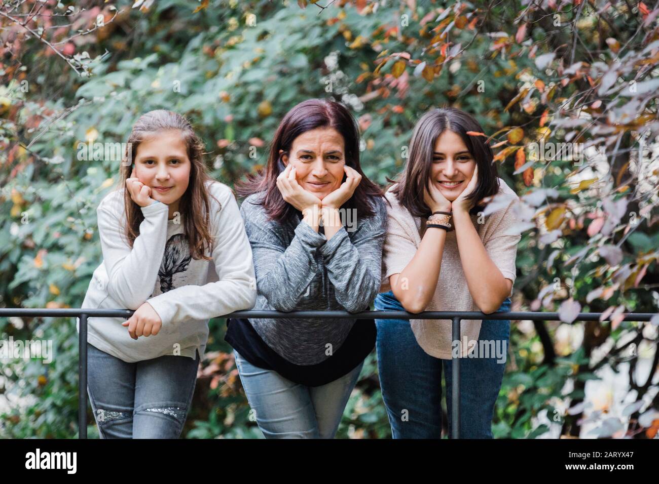 Madre e figlie sorridono e si appoggiano alla ringhiera Foto Stock