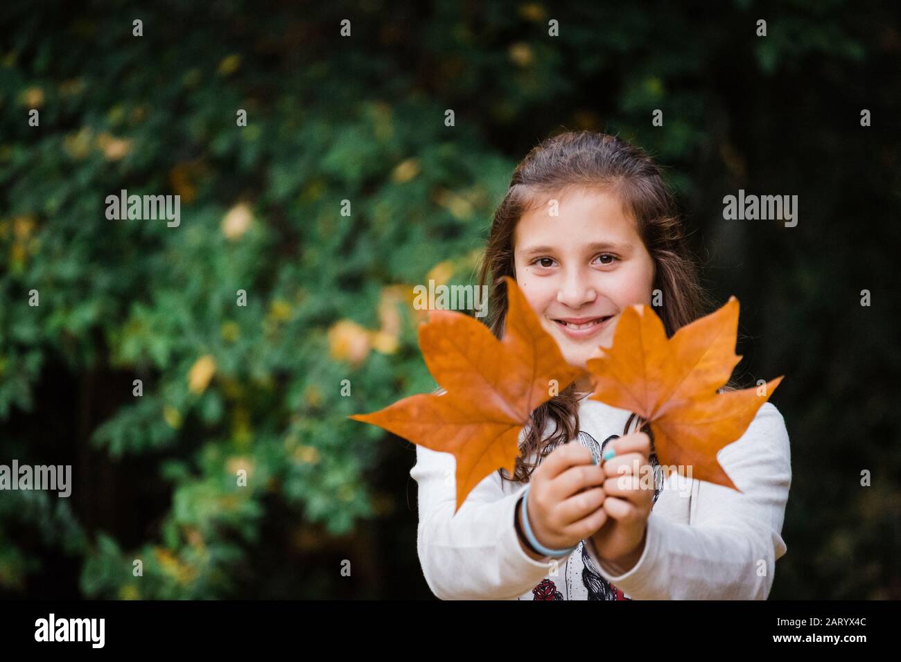 Sorridente ragazza che tiene foglie d'autunno Foto Stock