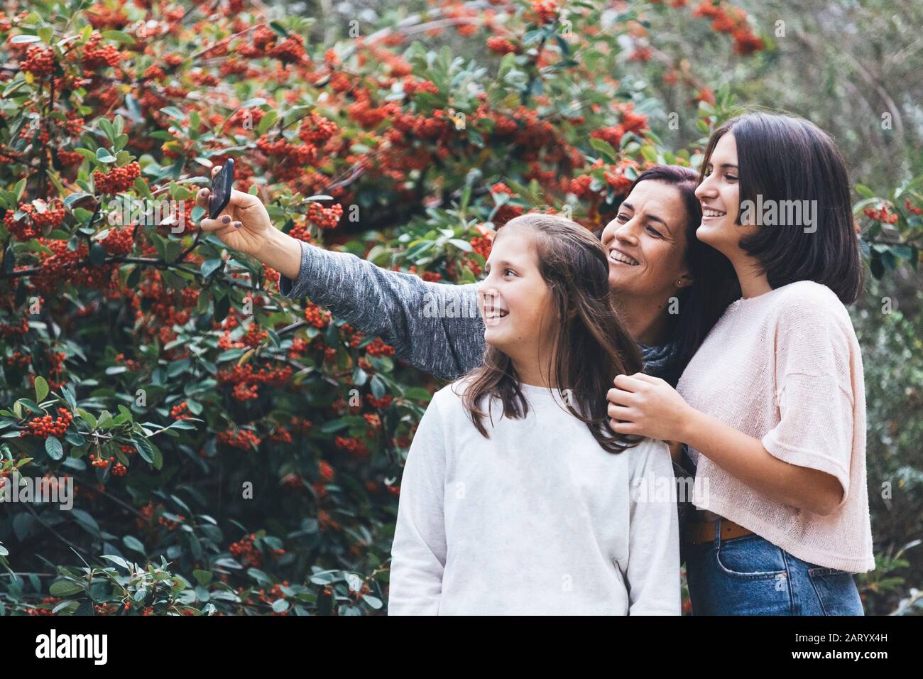 Madre e figlie sorridono e prendono selfie Foto Stock