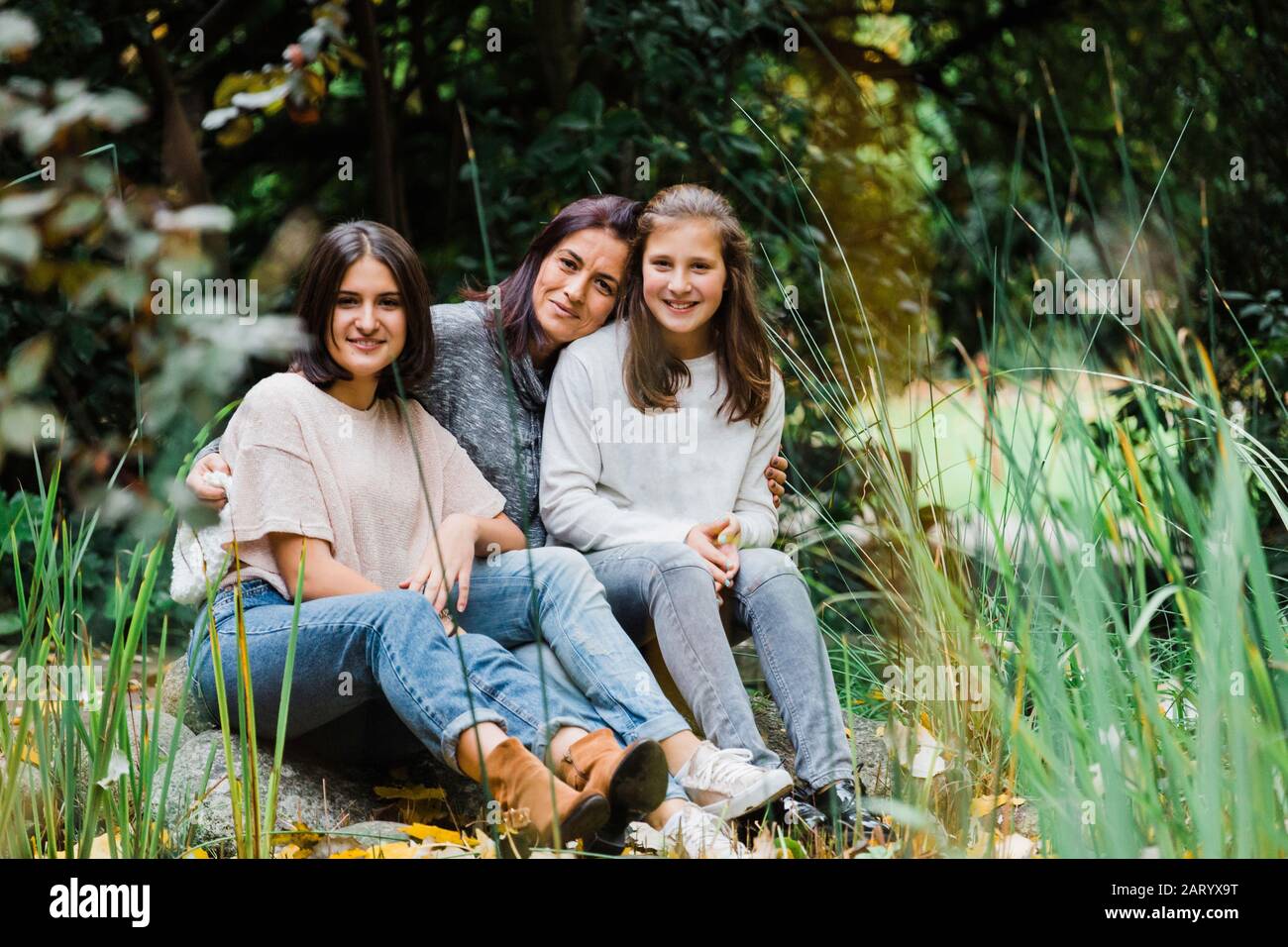 Madre e figlie abbracciano l'erba Foto Stock