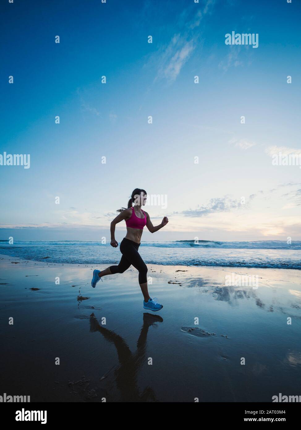 Giovane donna in esecuzione sulla spiaggia Foto Stock