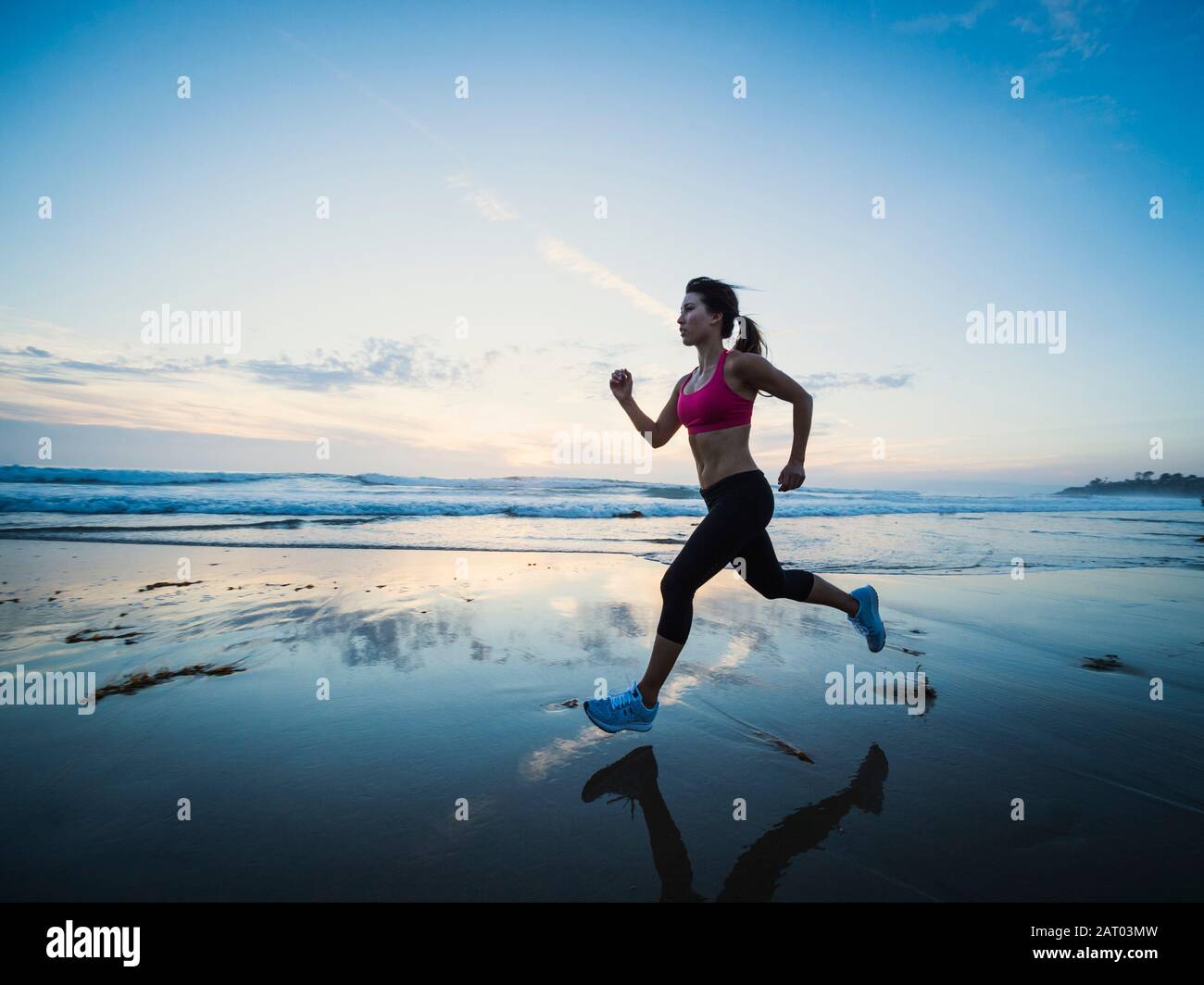 Giovane donna in esecuzione sulla spiaggia Foto Stock