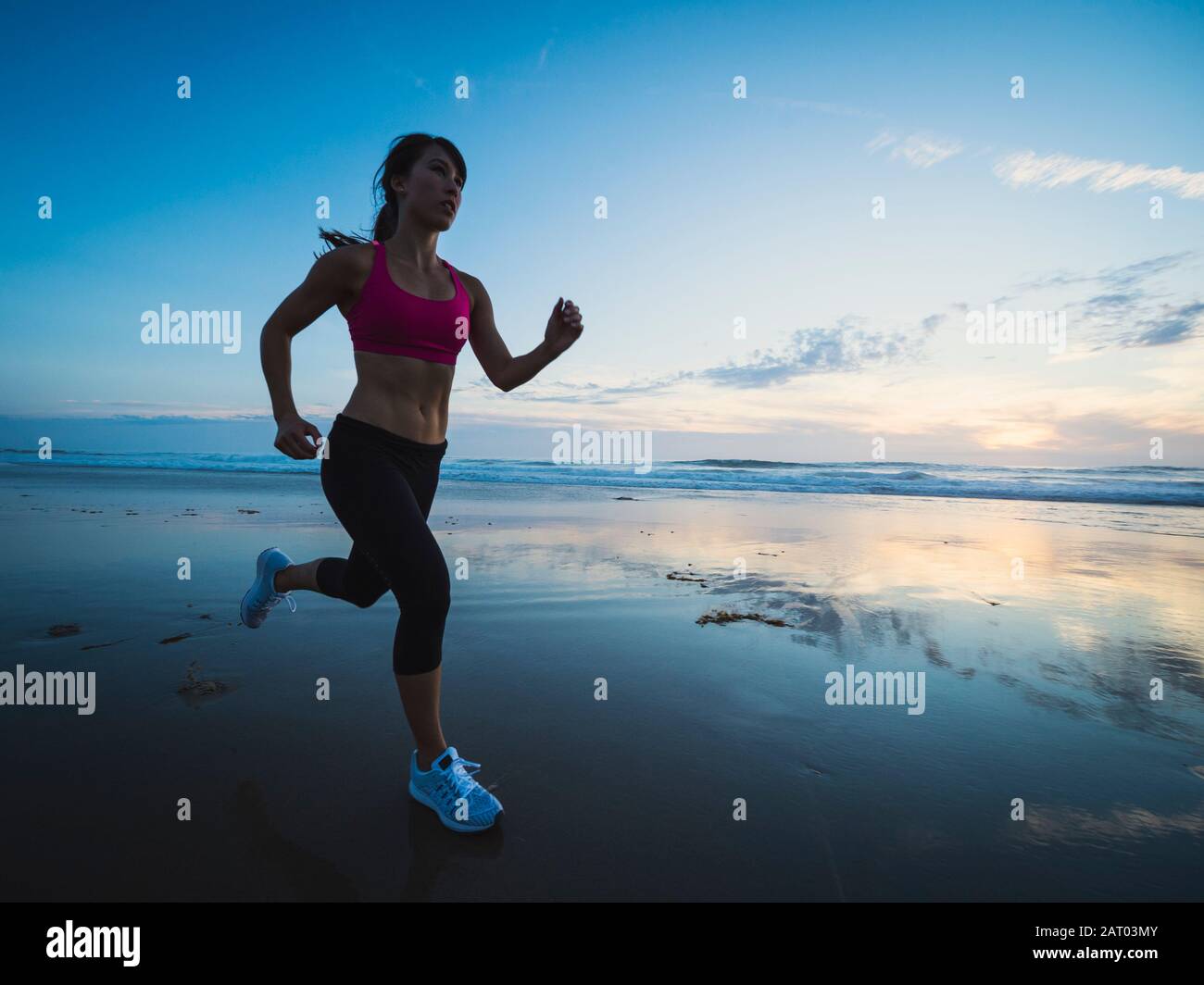 Giovane donna in esecuzione sulla spiaggia Foto Stock