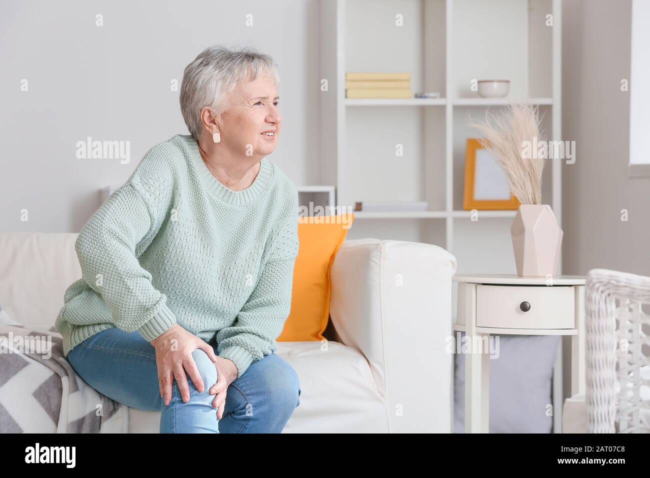 Donna anziana che soffre dal dolore nel ginocchio nel paese Foto Stock